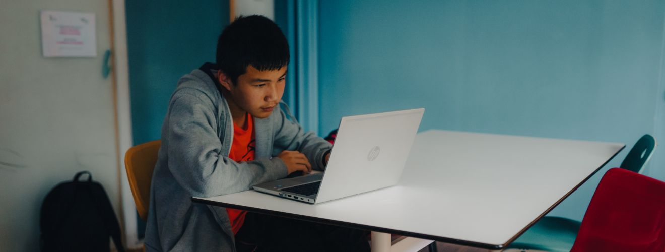 Un estudiant davant de la pantalla del seu ordinador en el que sembla una aula ordinària.