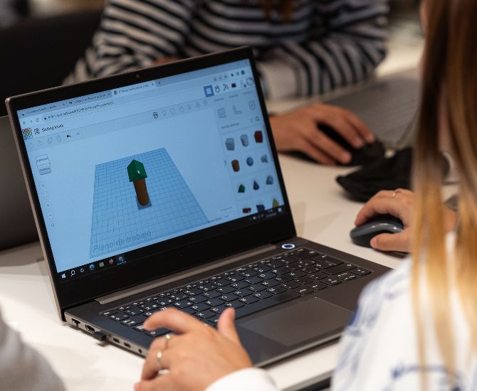 Es veu una professora d'esquenes realitzant una activitat de disseny 3D a l'ordinador.